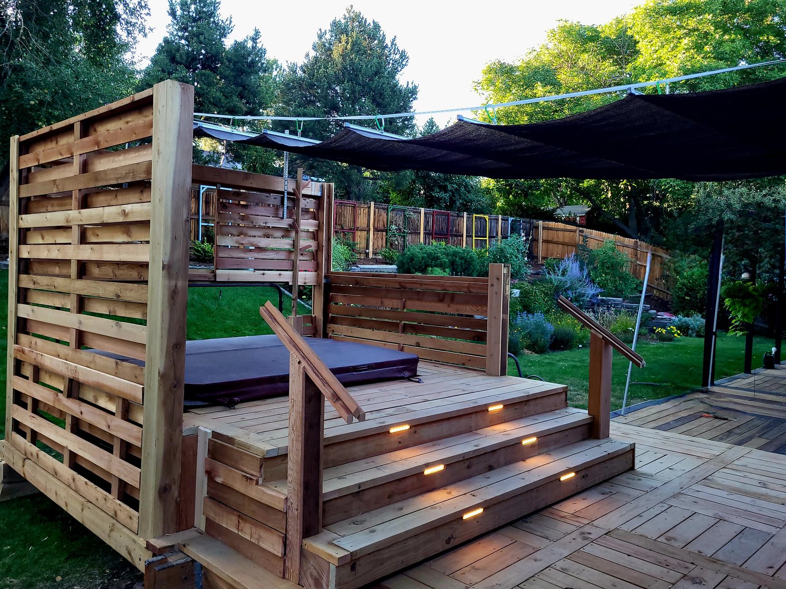 Finished hot tub deck surround with privacy screen and stair lighting in the Denver metro